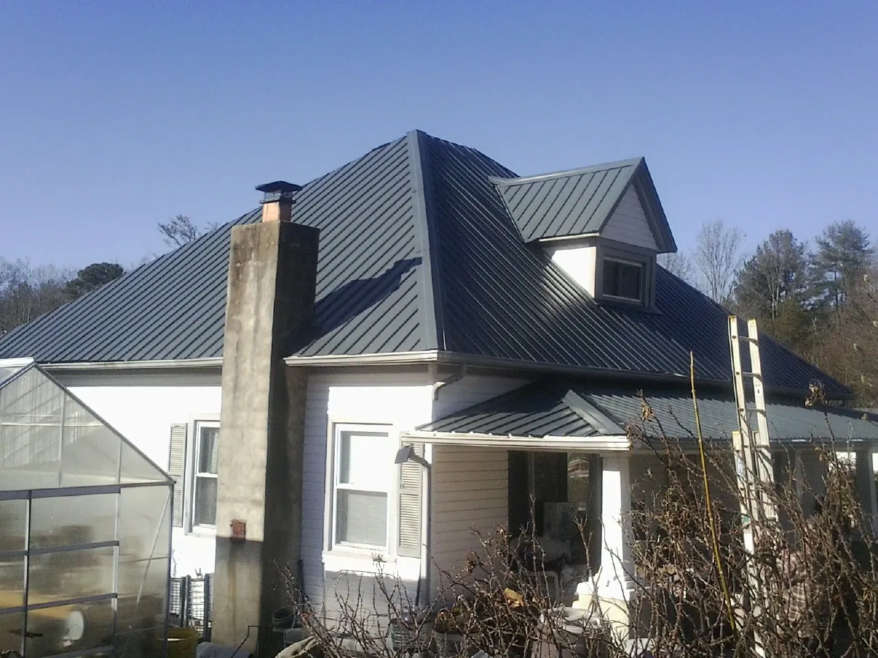 Dark blue standing seam metal roof on a white farmhouse with dormer — Slate & Tile Roof Repair by Roofing Brothers in Berkley
