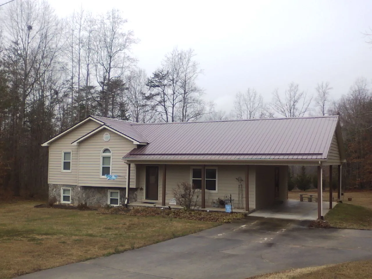 Burgundy metal roof on a tan split level home with an attached carport in Berkley