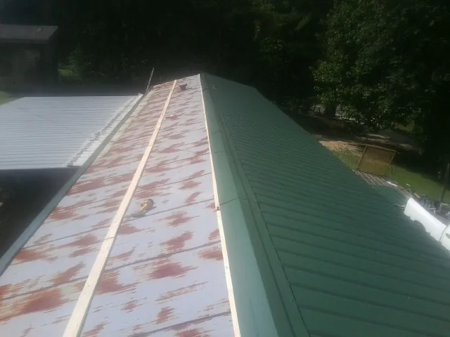 Old rusted panels beside newly installed green metal roofing — Wind Damage Roof Repair by Roofing Brothers in Berkley