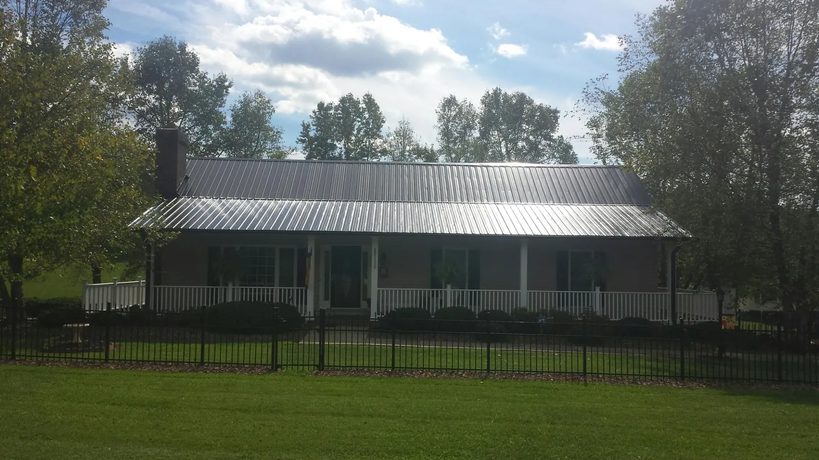 Gray metal roof on a brick ranch with a full width front porch — Gutter Guard Installation work by our crew in Berkley