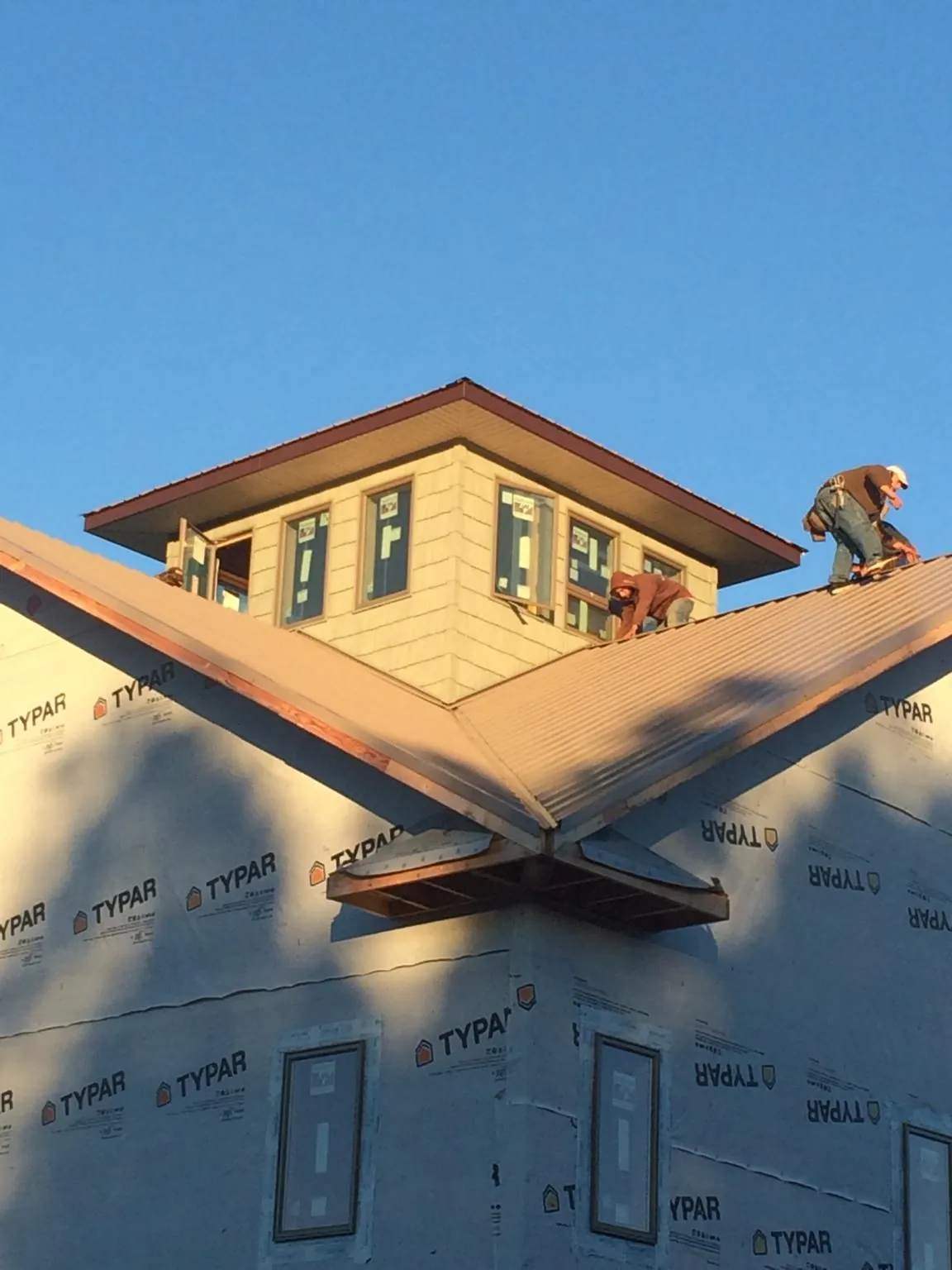 Roofers working around a rooftop cupola on a new metal roof at sunset — Roof Waterproofing in Berkley by Roofing Brothers